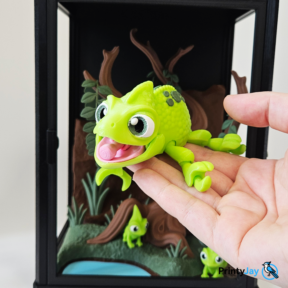 Articulated green chameleon 3D print in hand inside terrarium - PrintyJay